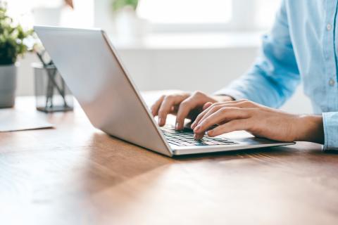 Person sitting at a desk typing on their laptop